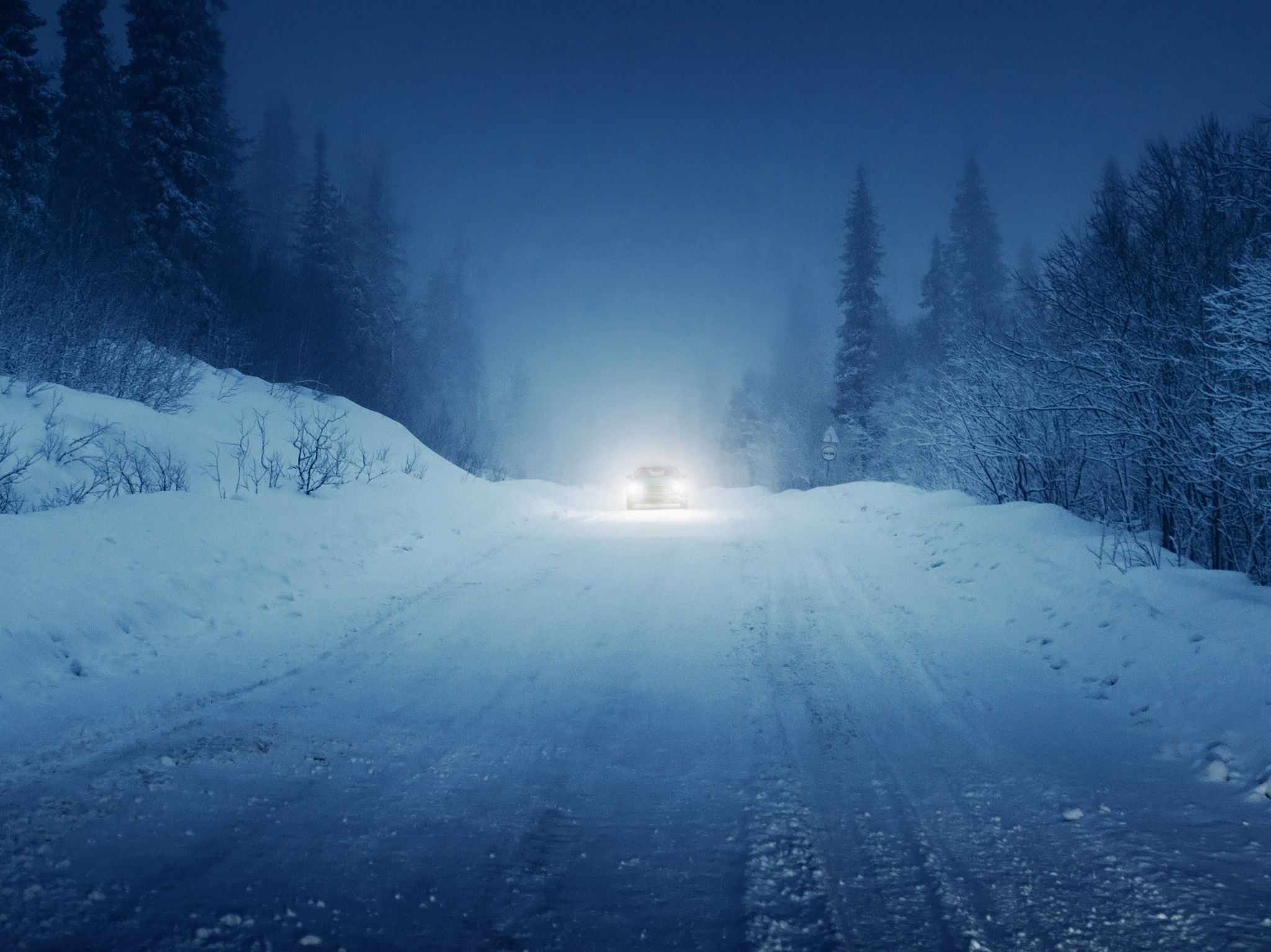 lights of car and winter road in forest